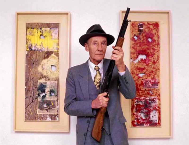 William Burroughs posing with two 'shotgun paintings'