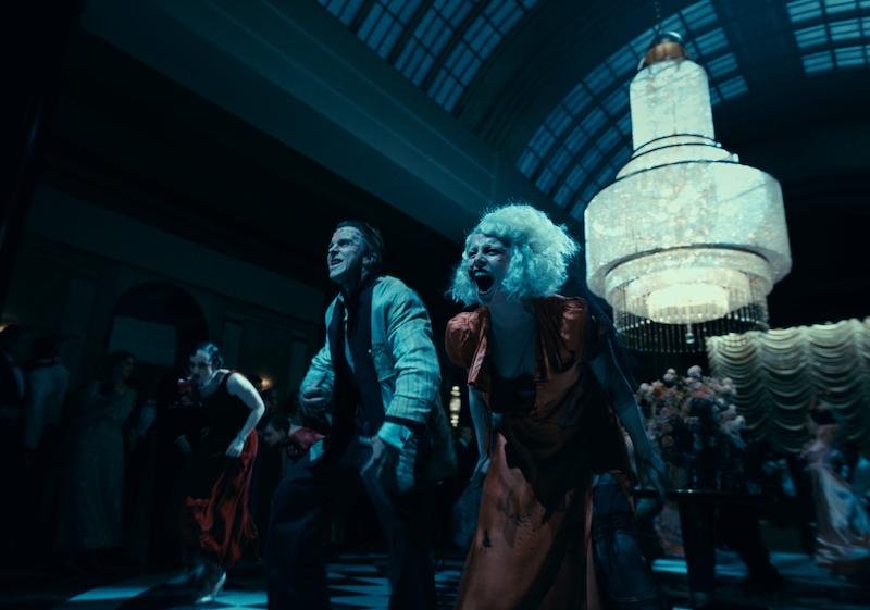 Christian Bale and Jessie Buckley, as Frank and The Bride, dancing in a club, with others dancing around them